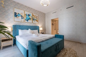 Une chambre à coucher moderne avec un grand lit, une table de chevet, une commode et un dressing.