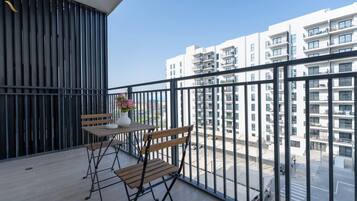 Un balcón con una mesa y sillas, un florero con flores y vistas a un edificio residencial.