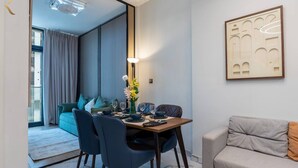 Ett modernt matområde med ett bord för två personer, en soffa och en dekorativ väggdekoration.