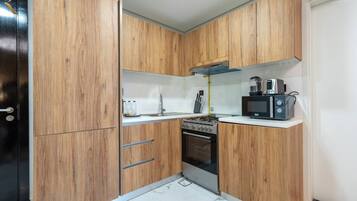 Une cuisine de taille réduite, dotée de meubles en bois, d’une cuisinière, d’un four, d’un four à micro-ondes et d’un évier.
