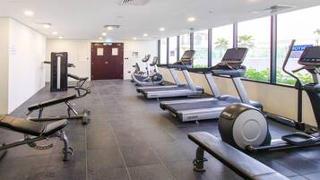 Une salle de sport équipée de tapis de course, de vélos elliptiques et de bancs de musculation.