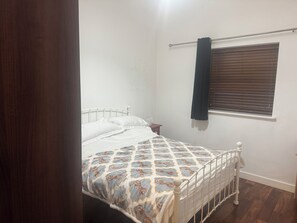 A bedroom with a bed, a window with blinds, a curtain, and a wooden floor. - Spacious Dublin City Centre 2 Apartment w/Gym on site. (Dublin)