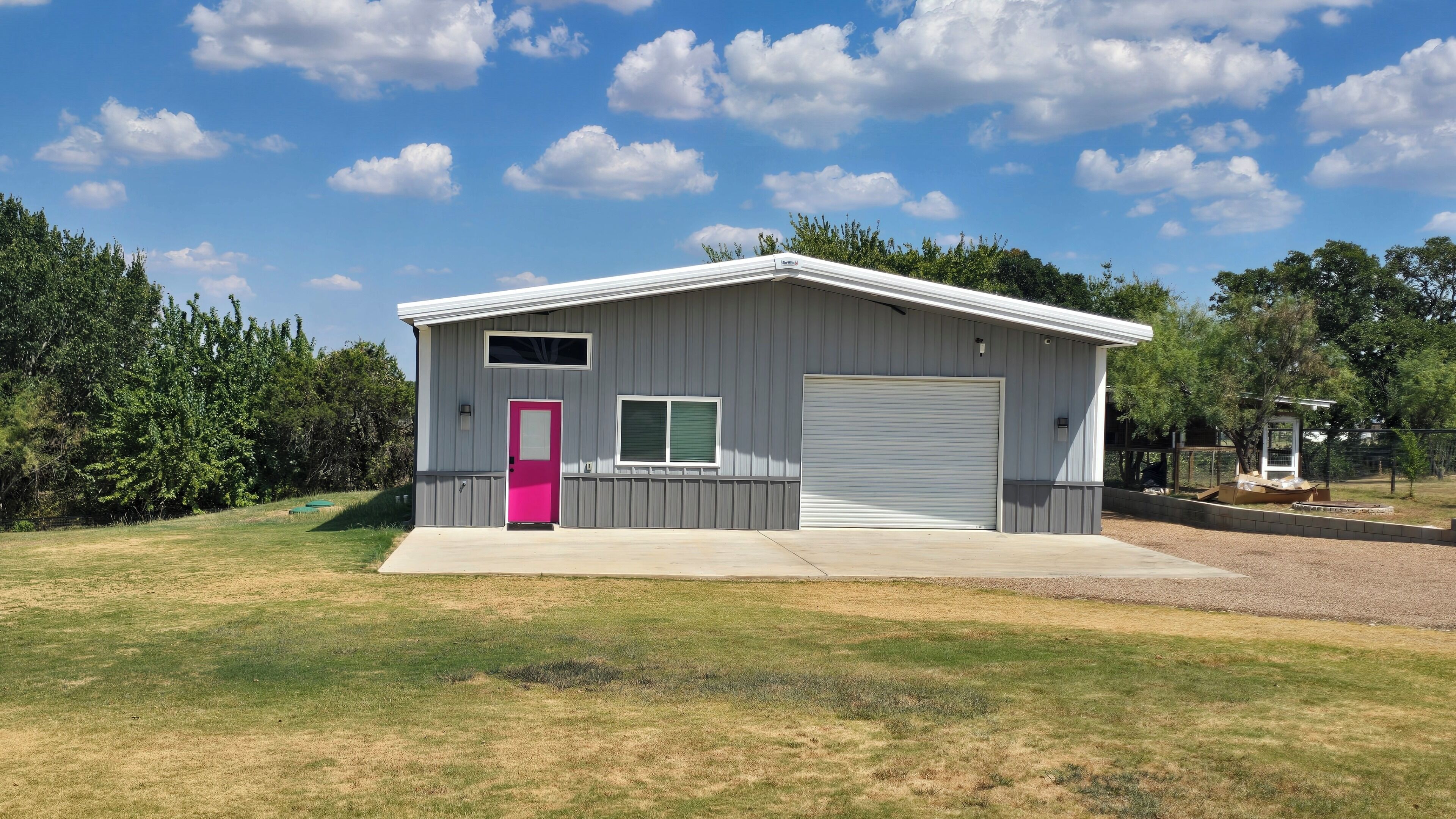 A single-story building with a garage, a pink door, and a window.