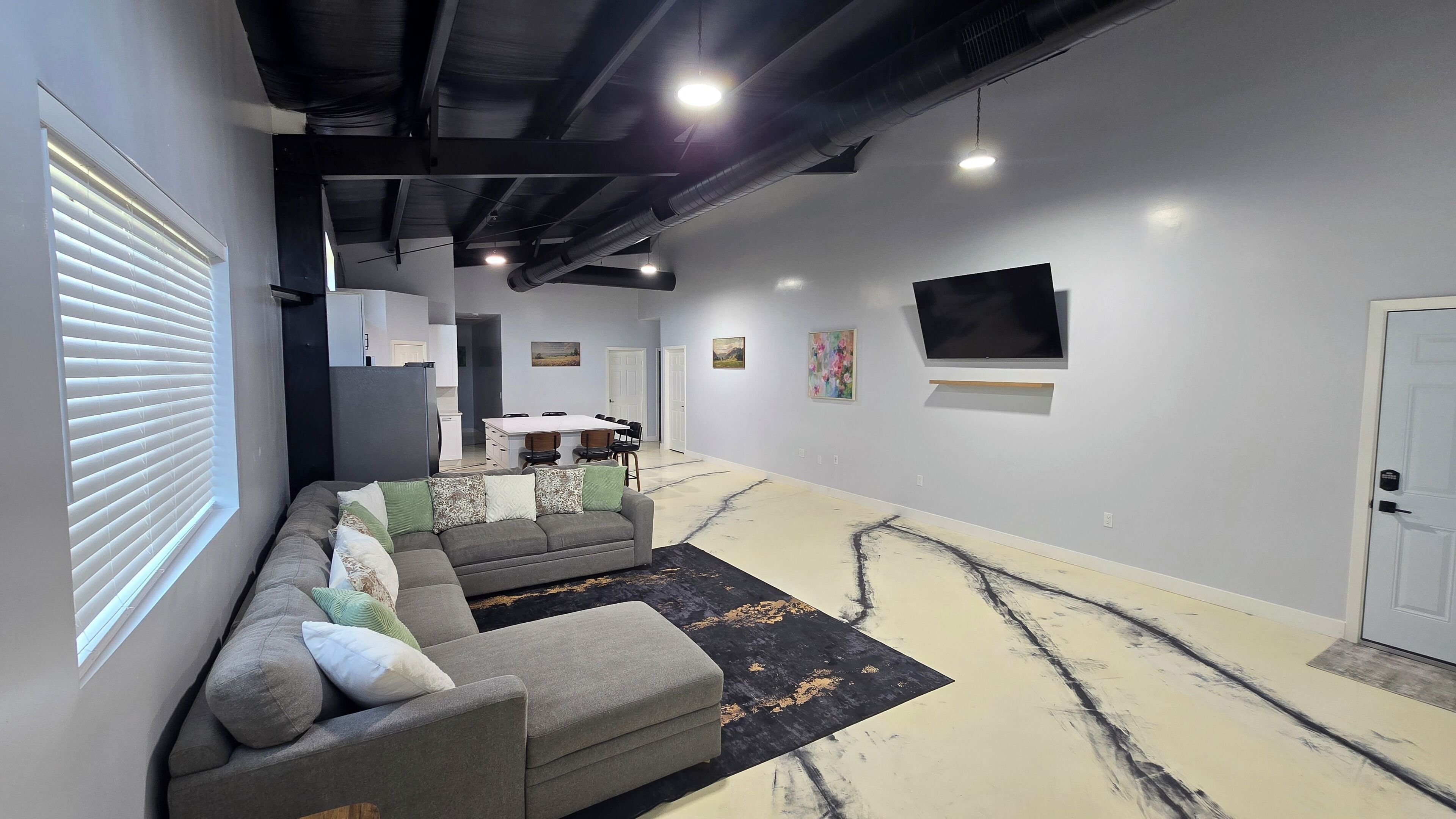 Ein modernes Wohnzimmer mit einem grauen Ecksofa, einem schwarzen und goldenen Teppich und einem flachbildfernseher, der an der Wand montiert ist.