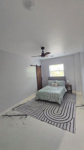 A bedroom with a bed, a ceiling fan, a window, and a nightstand. - Spacious Barndominium in Poolville (Poolville)