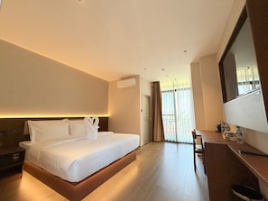 A hotel room with a large bed, a desk, and a television. - Juris Park Hotel (Kigali)