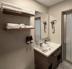 A modern bathroom with a vanity, towel rack, and a shower. - Juris Park Hotel (Kigali)
