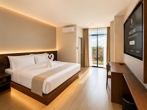 A hotel room with a bed, bedside table, desk, and a television screen displaying a welcome message. - Juris Park Hotel (Kigali)