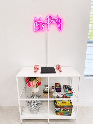 A white shelf with a neon sign that reads 'Let's Party' above it. - The Velvet Retreat | Glam Escape w/ Beauty Lounge (Tampa)