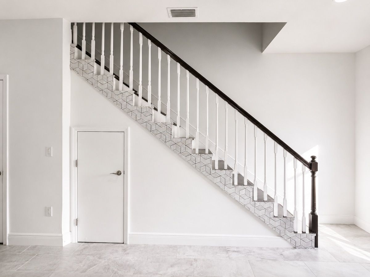 A staircase with a geometric patterned floor and white balusters.