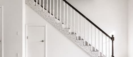 A staircase with a geometric patterned floor and white balusters.