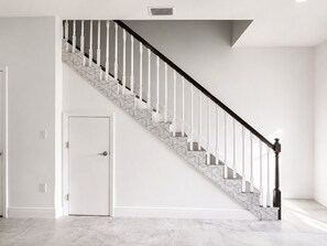 A staircase with a geometric patterned floor and white balusters.