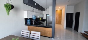 A modern kitchen with a black countertop, white cabinets, and a hanging plant.