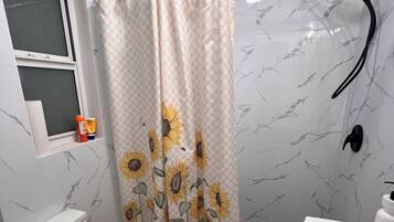 Un baño con inodoro, ducha con cortina de girasol y lavabo.