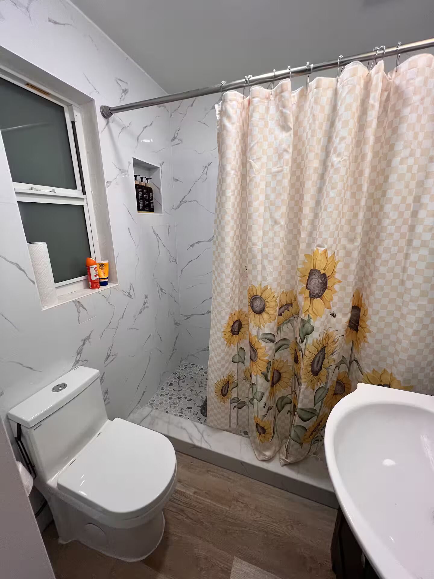 A bathroom with a toilet, sink, and shower curtain with a sunflower pattern.