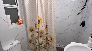 A bathroom with a toilet, a shower with a sunflower curtain, and a sink.