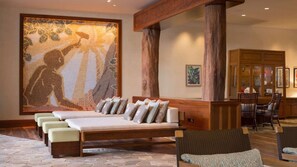 Una stanza spa con un grande murale, una testata del letto in legno e un’area salotto con poltrone e divano.