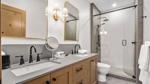 A modern bathroom with a vanity, sink, mirror, and shower area. - Switchback Creek by Sun Peaks Alpine Getaways (Sun Peaks)
