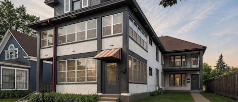 A modern two-story house with a large front porch and a well-maintained lawn.