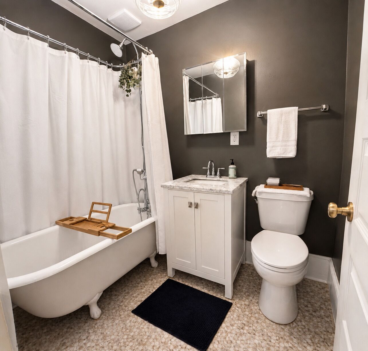 A bathroom with a freestanding bathtub, a sink with a mirror above it, and a toilet.