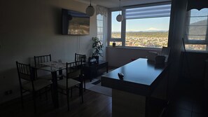 A dining area with a table and chairs, a potted plant, and a view of a cityscape through a window. - Apartment in Downtown Temuco (Temuco)