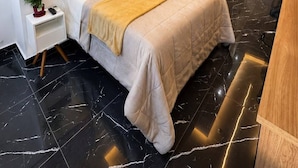 Ein modernes Hotelzimmer mit einem Bett, einem Nachttisch und einem Gemälde an der Wand.