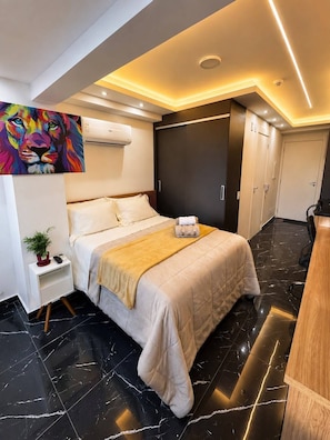 Habitació d'hotel moderna amb llit, taula de nit i un quadre a la paret.