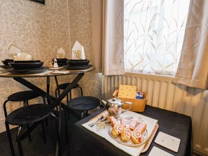 A dining table set with black plates, bowls, and a teapot, with a window with a view of buildings in the background. - 74 Trafalgar Square (Scarborough)