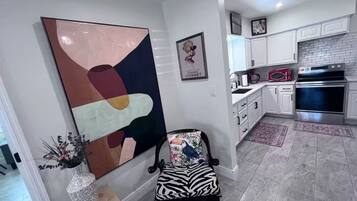 Una cocina moderna con armarios blancos, horno de acero inoxidable y microondas.
