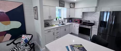 A modern kitchen with white cabinetry, a large island, and stainless steel appliances.
