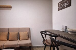 Una habitación con sofá, una mesa, sillas y un cartel en la pared.