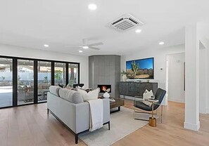 A modern living room with a sofa, a fireplace, and a television. - Charming 4-bedroom house in Scottsdale (Scottsdale)