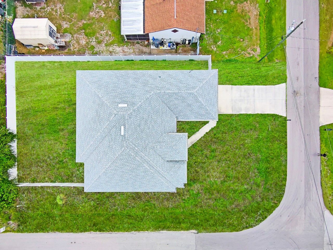 An aerial view of a property with a large, irregularly shaped building, a paved driveway, and a grassy area.