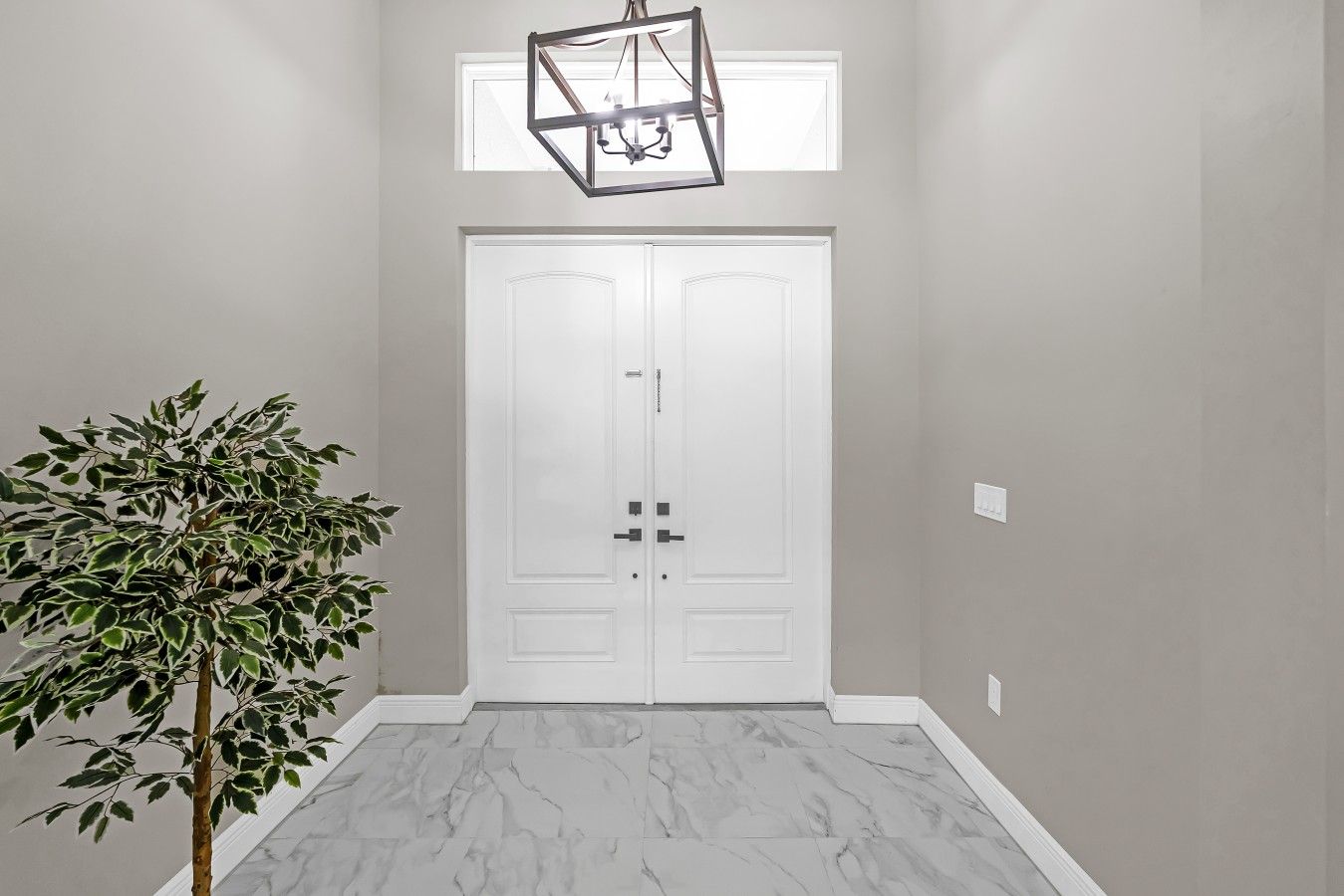 A hallway with a white door, a potted plant, and a geometric light fixture.