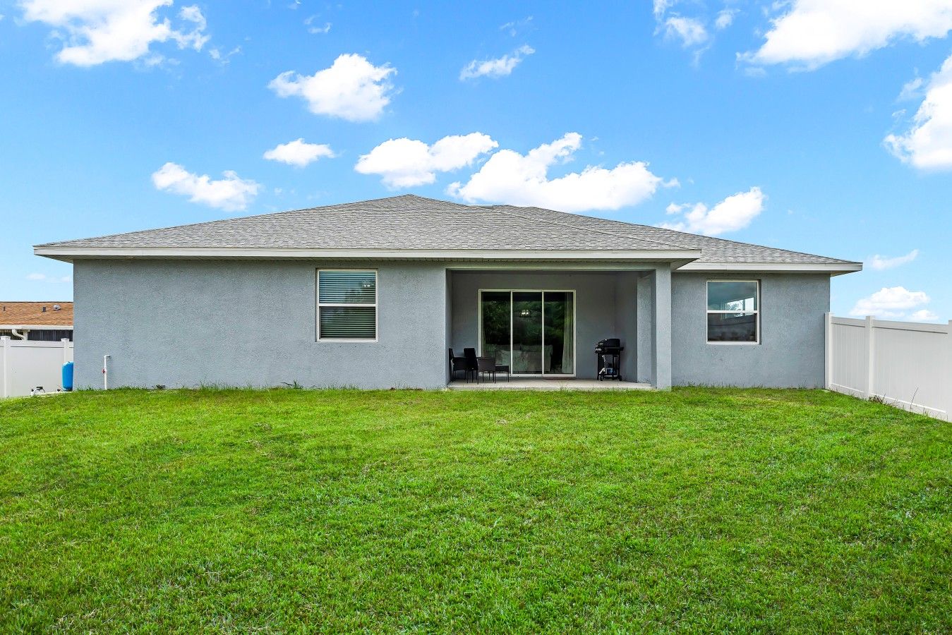 A single-story house with a flat roof, a covered patio area, and a fenced backyard.