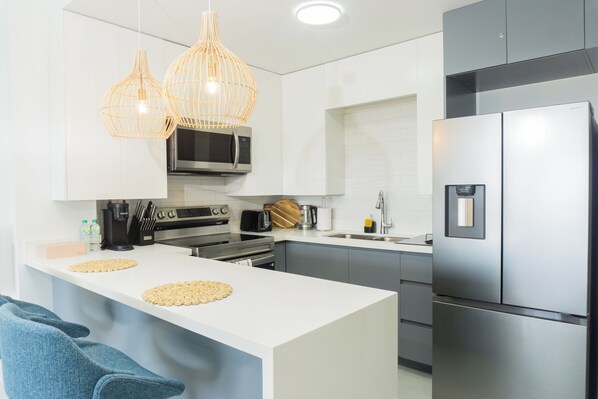 A modern kitchen with white cabinetry, stainless steel appliances, and a central island with woven placemats.