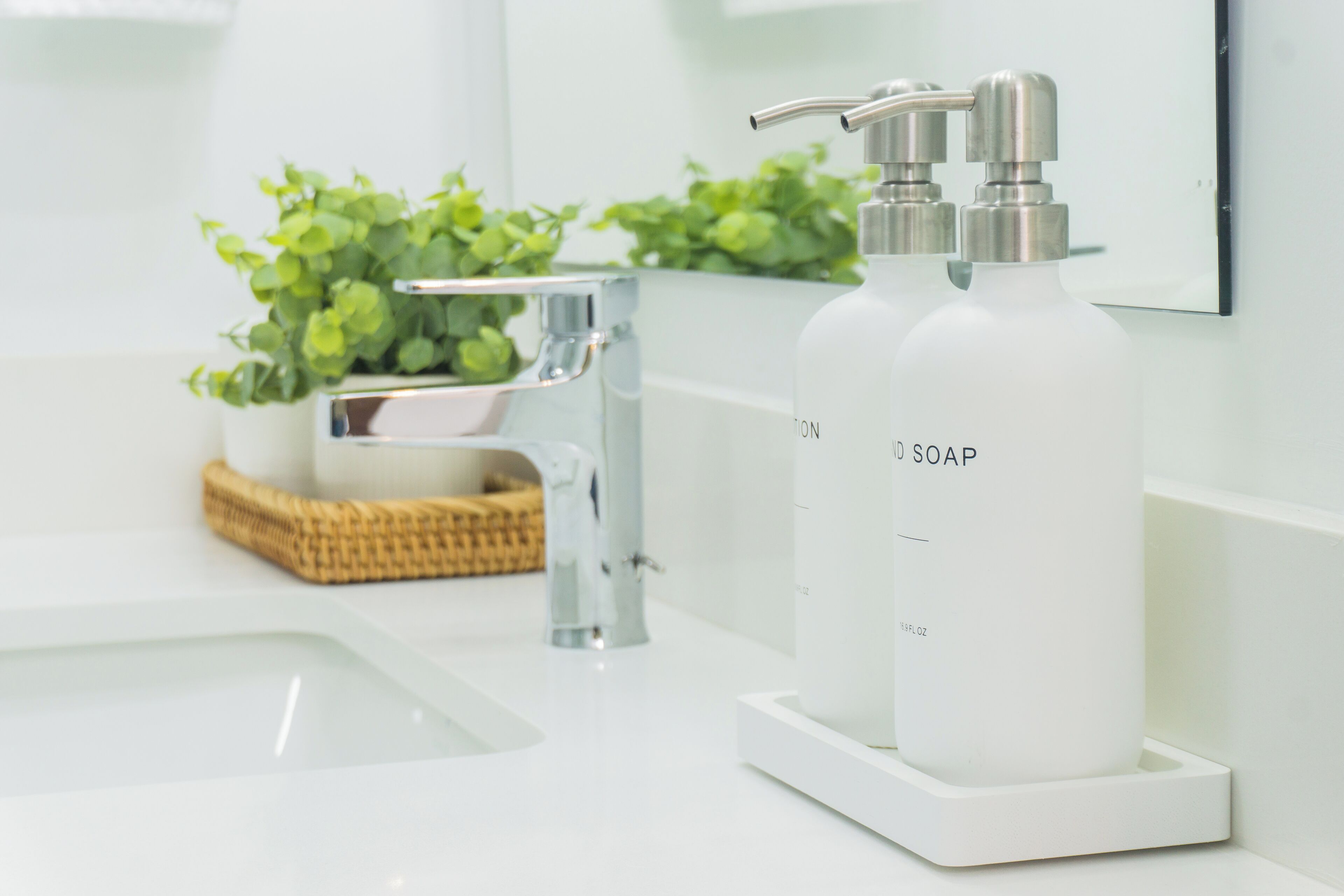 A bathroom with a white sink, a modern faucet, and a soap dispenser on a white tray.
