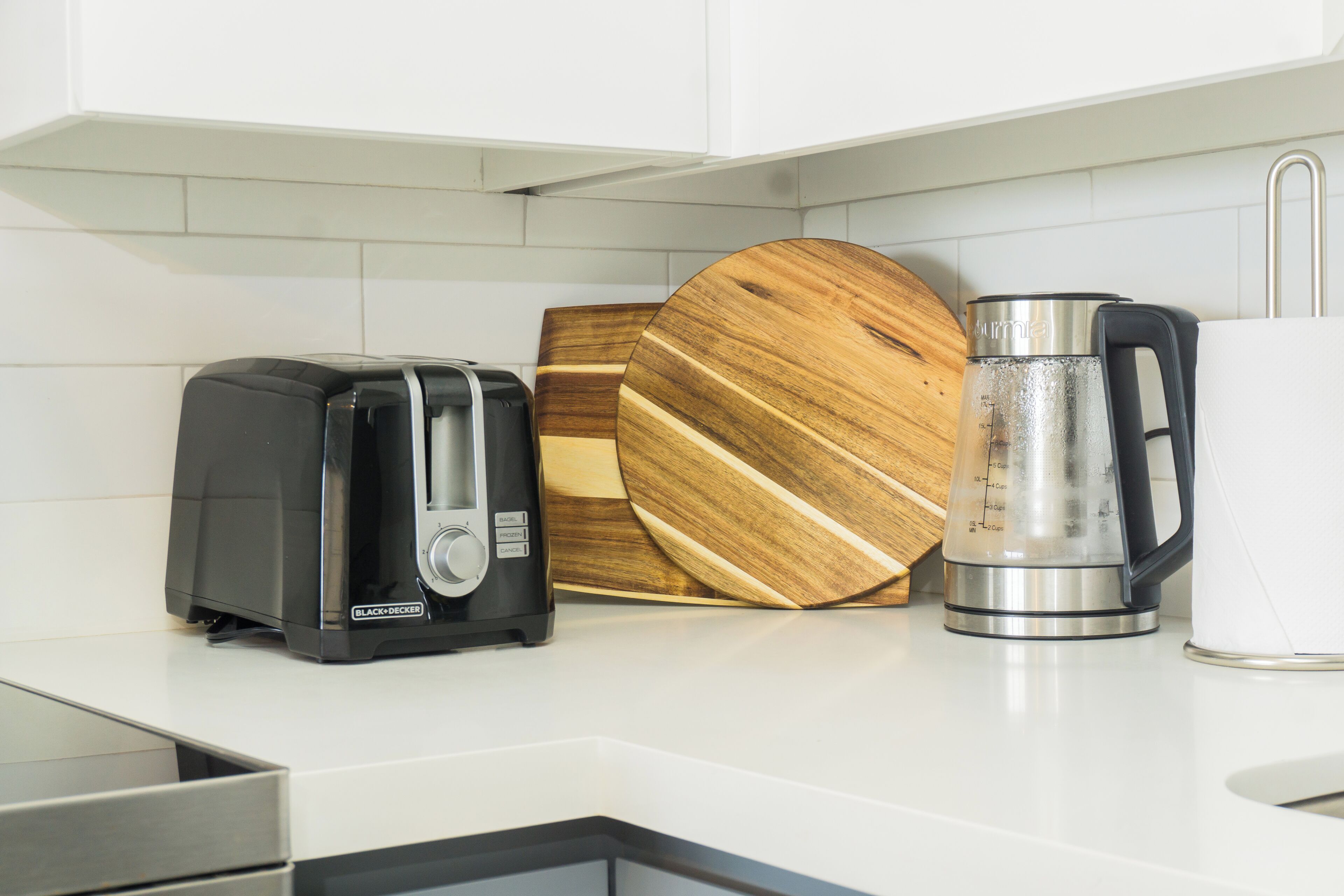 Une cuisine équipée d’un grille-pain, d’une planche à découper en bois et d’une cafetière en acier inoxydable.