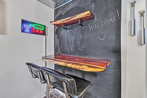 A bar area with a neon sign, wooden shelves, and a chalkboard with 'WELCOME!' written on it. - Gorgeous lake views from every level! (Huddleston)