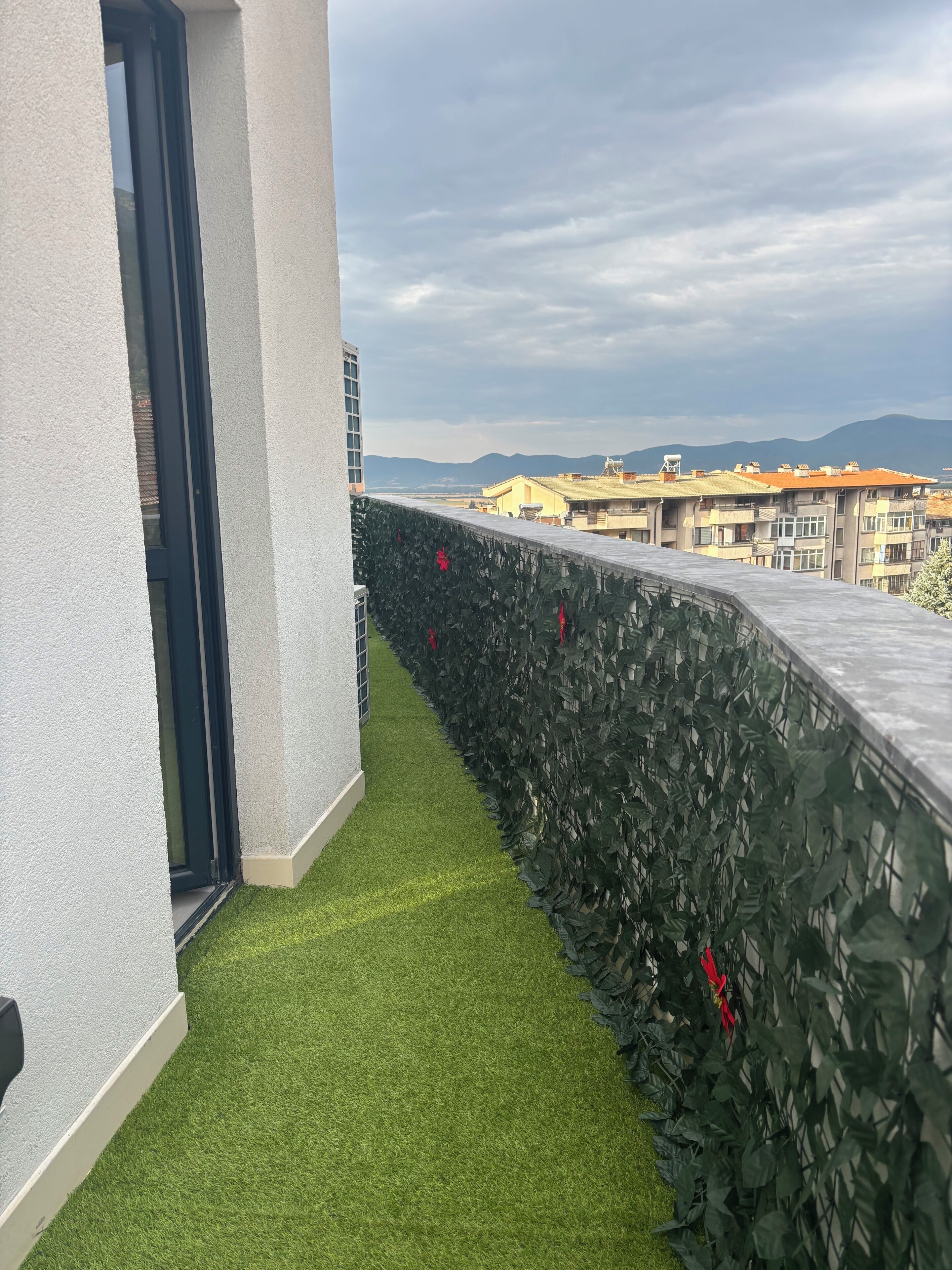 Un balcon agrémenté d’un revêtement de gazon synthétique et d’un mur végétal.