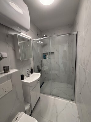 Une salle de bain moderne avec une douche à parois de verre, un lavabo blanc et un miroir au-dessus.