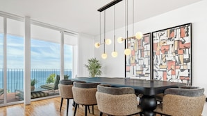 Un comedor moderno con una mesa grande, seis sillas y vista al océano.