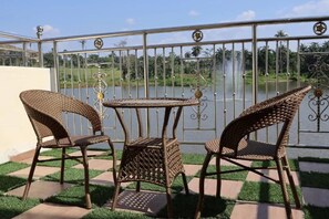 A balcony with wicker furniture and a view of a lake.