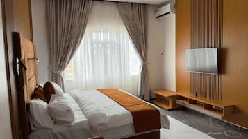 Una habitación de hotel moderna con cama, cortinas, televisor y pared de paneles de madera.