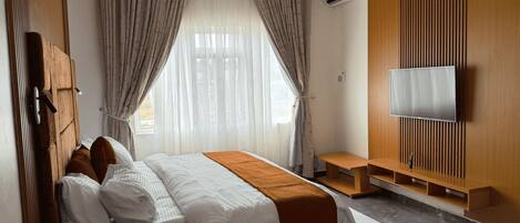 Una habitación de hotel moderna con cama, cortinas, televisor y pared de paneles de madera.