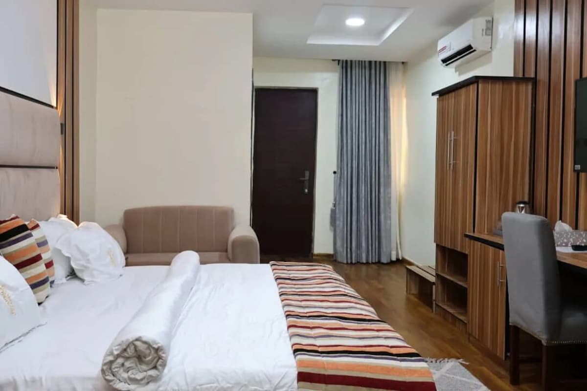 Una habitación de hotel con cama, escritorio, silla, armario y puerta.