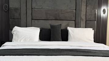 Una cama con cabecera oscura, almohadas blancas y oscuras, y una manta negra.