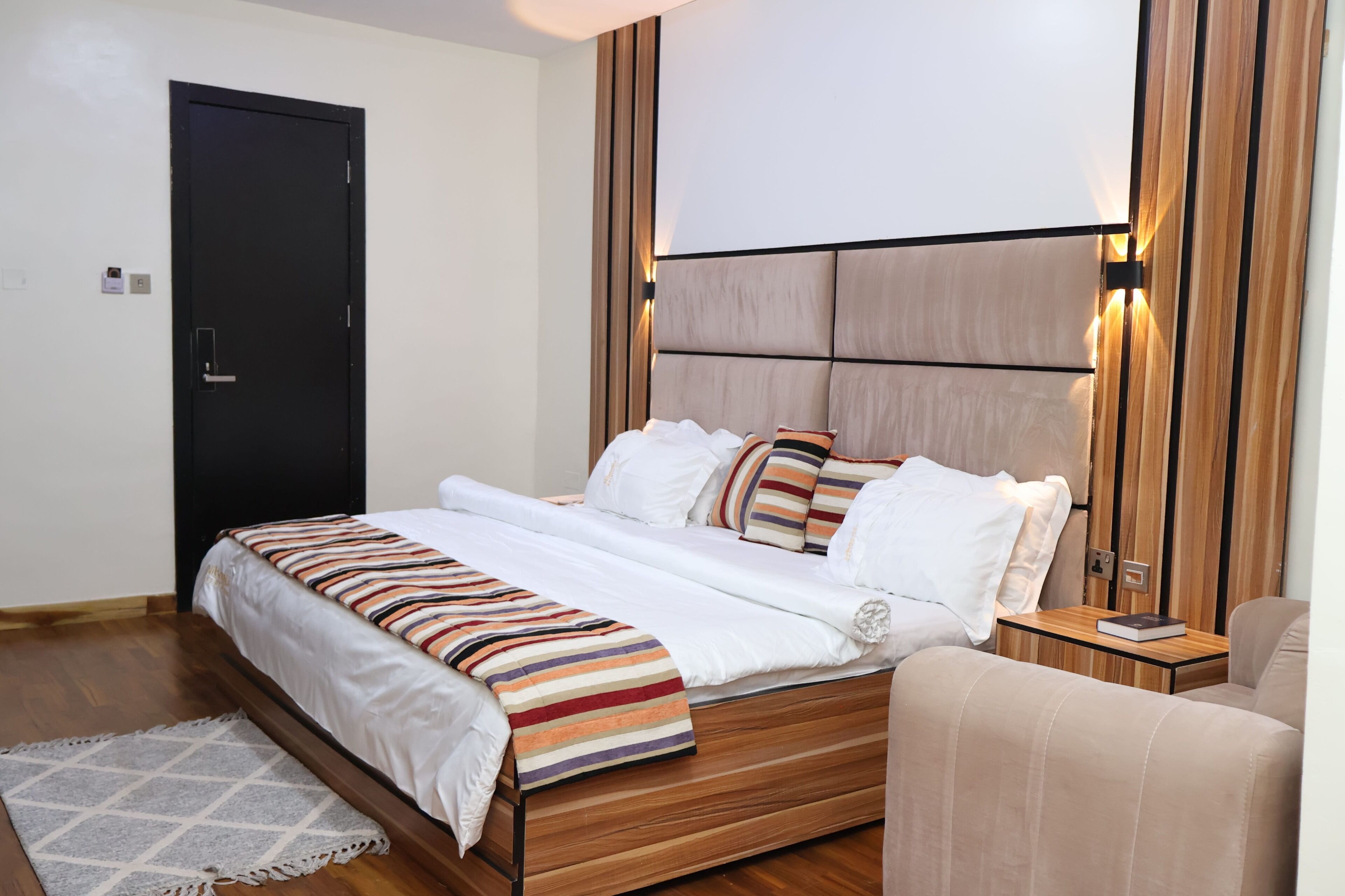 A modern bedroom with a wooden bed, white bedding, and a striped throw blanket.