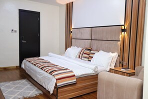 Un dormitorio moderno con una cama de madera, ropa de cama blanca y una manta a rayas.