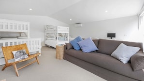 Ein modernes Wohnzimmer mit einem braunen Sofa, einem weißen Kinderbett und einem Korbstuhl.